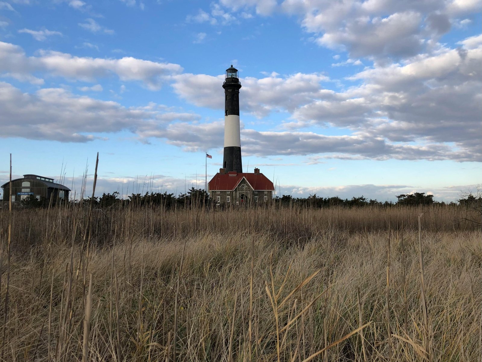 Beautiful view of Fire Island Lighthouse with a golden sky and field. Iconic New York landmark.